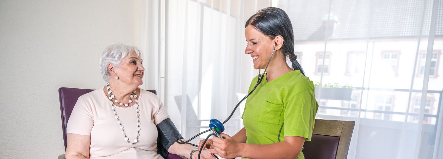 Pflegerin misst Bewohnerin Blutdruck